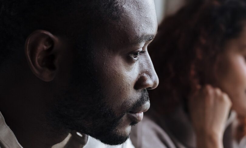 A thoughtful couple sits indoors, capturing a moment of introspection and connection.